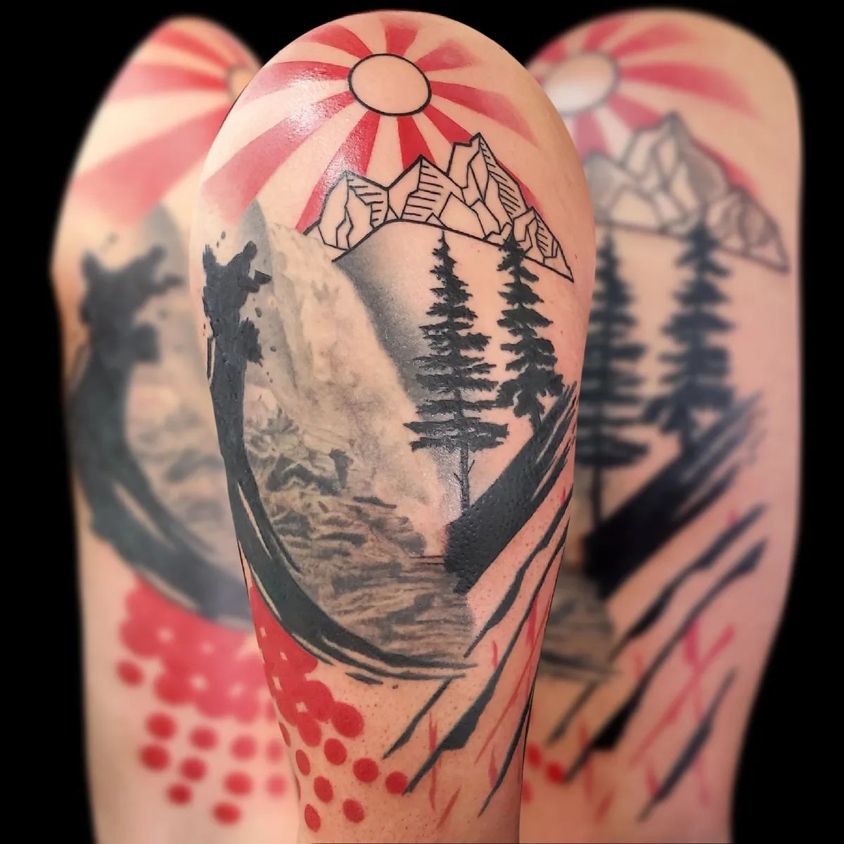A tattoo on an arm depicting a dramatic landscape with a radiating sun, jagged outlined mountains, a cascading waterfall, silhouetted evergreen trees, and bold red dot and brushstroke accents in the lower section, blending Japanese woodblock and contemporary styles.