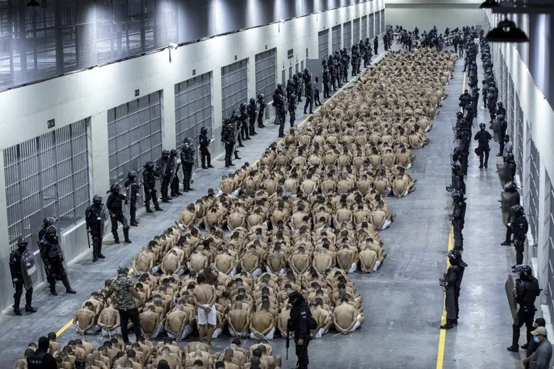 Prisoners in CECOT, dressed in identical uniforms, sit on the floor under the supervision of guards. Photo: U.S. News & World Report.