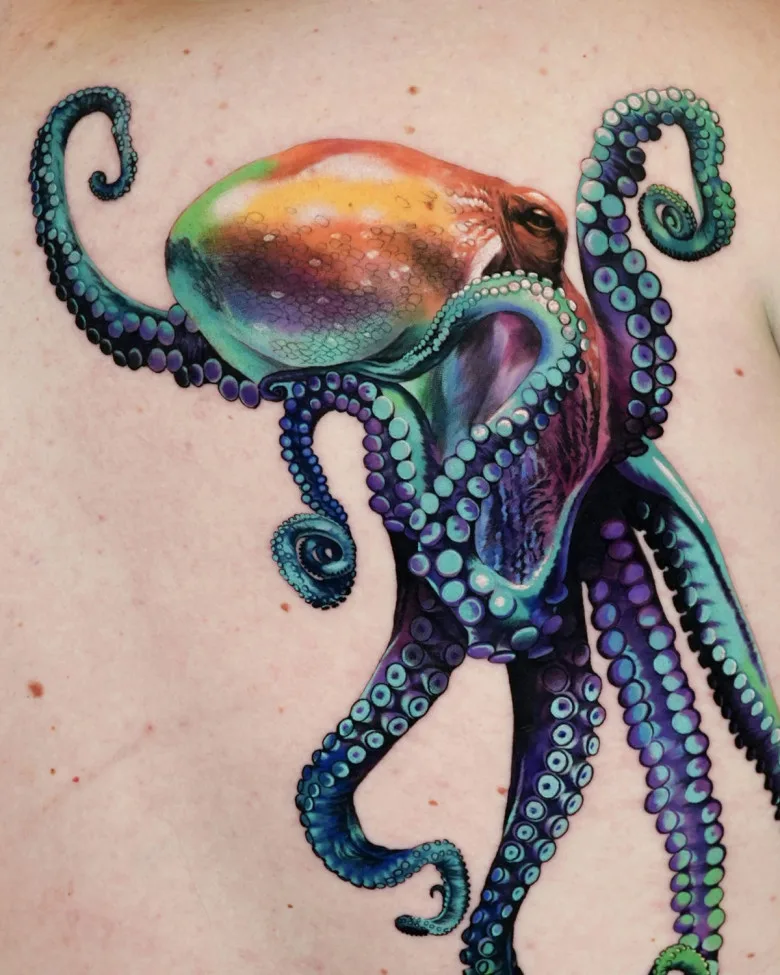 Octopus Tattoo – A hyper-realistic tattoo of an octopus in rich shades of blue, purple, and orange, with detailed textures and lifelike shading. The placement on the ribcage enhances the fluidity of the design.