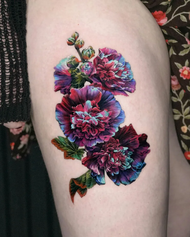 Peony Flowers Tattoo – A tattoo of large, deep pink and purple peonies with lush green leaves, placed on the upper thigh. The piece is highly detailed, with soft color transitions creating a realistic effect.