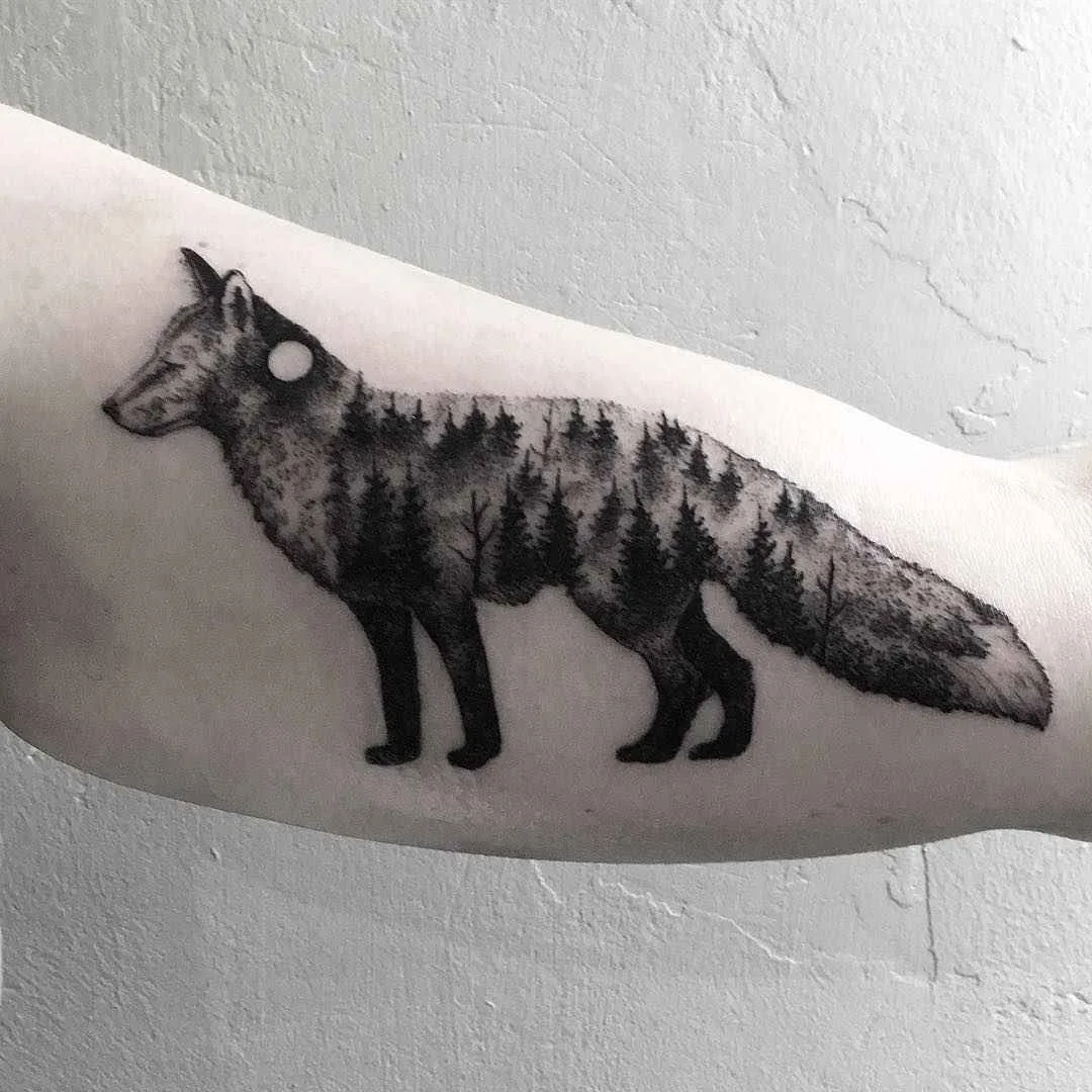 A black and grey tattoo of a fox with a detailed forest scene incorporated into its body, rendered in a highly detailed illustrative style.