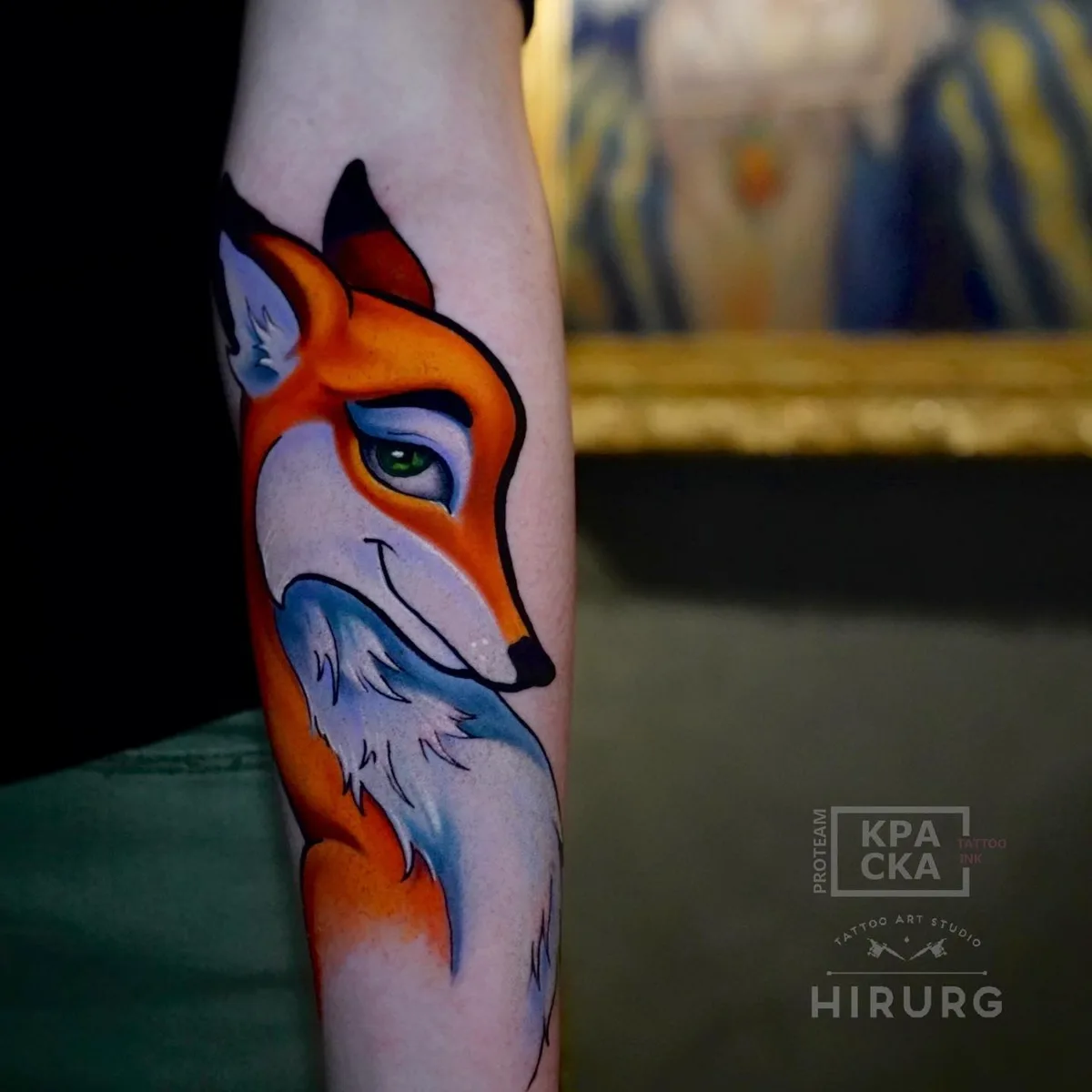 A colourful cartoon fox tattoo on the forearm, depicted in bright orange, white, and blue with bold outlines.