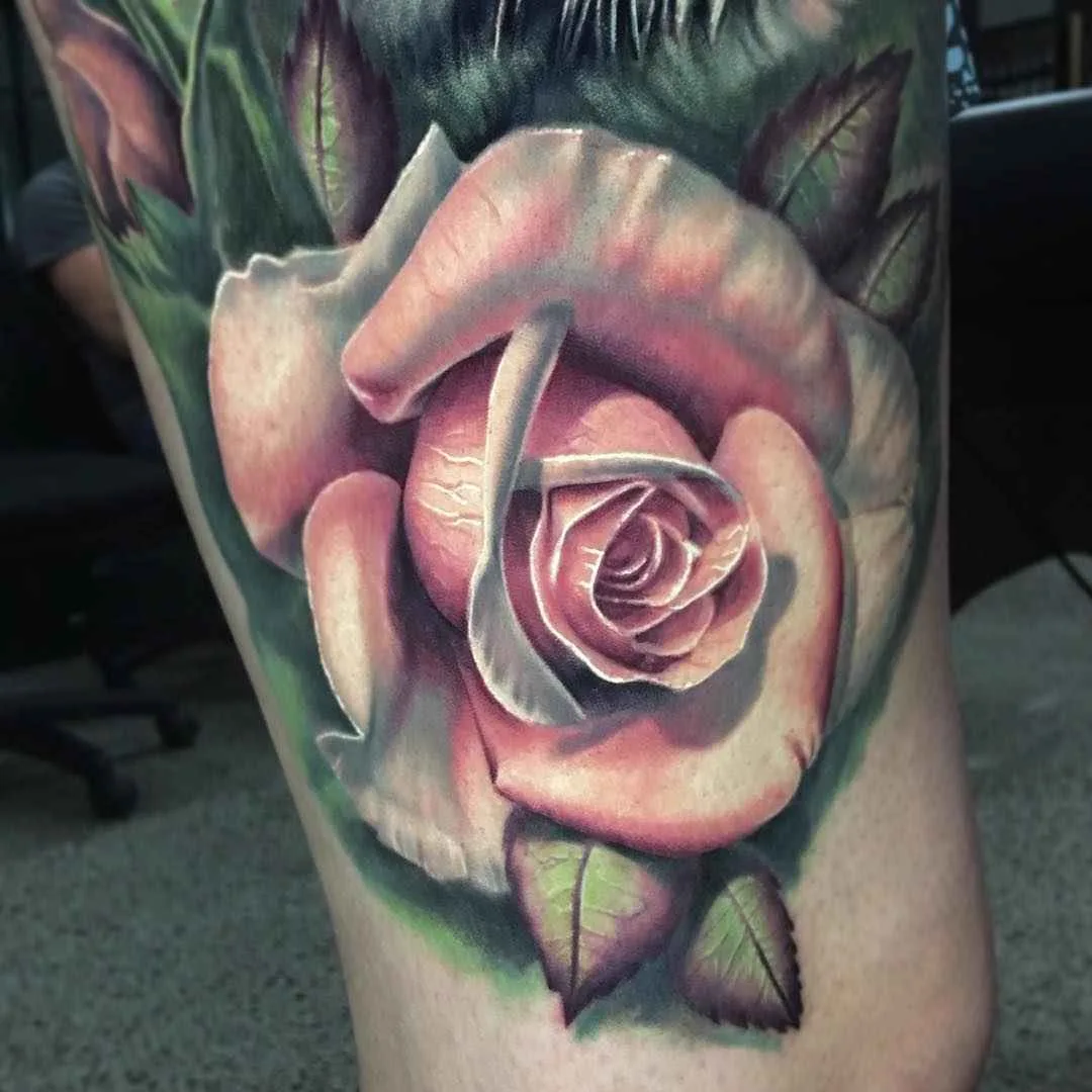 Ein detailliertes Farbtattoo einer weißen Rose mit geschichteten Blütenblättern und grünen Blättern, in realistischer Schattierung auf der Haut dargestellt.