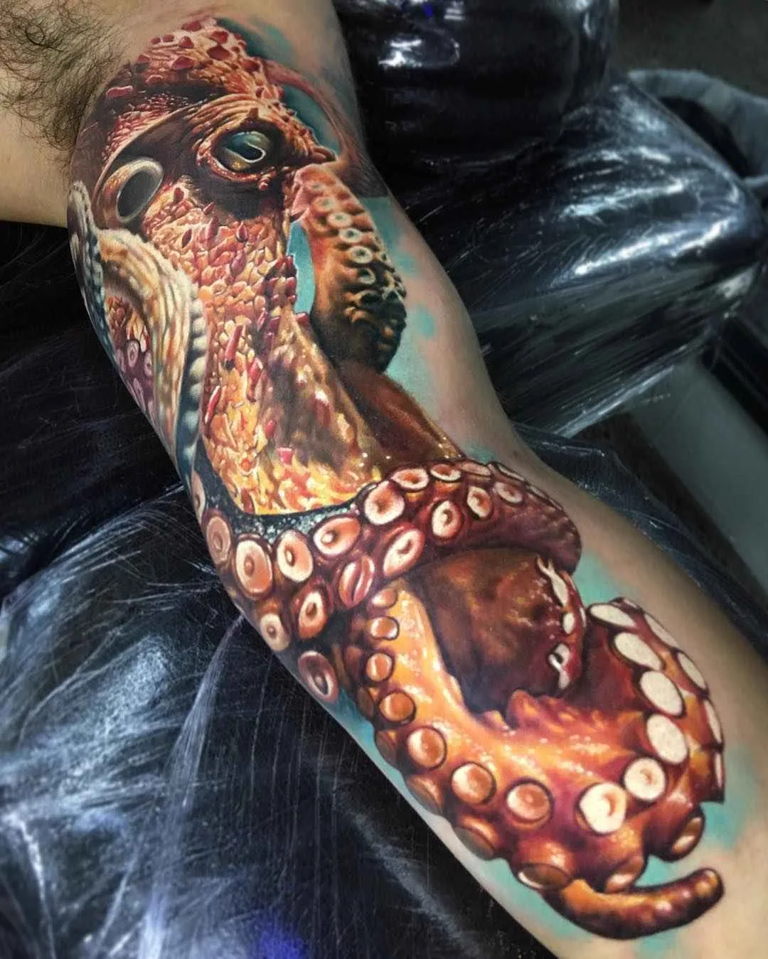 A hyperrealistic octopus tattoo rendered in vibrant colours with intricate surface detail, showing the animal's textured skin and suckers.