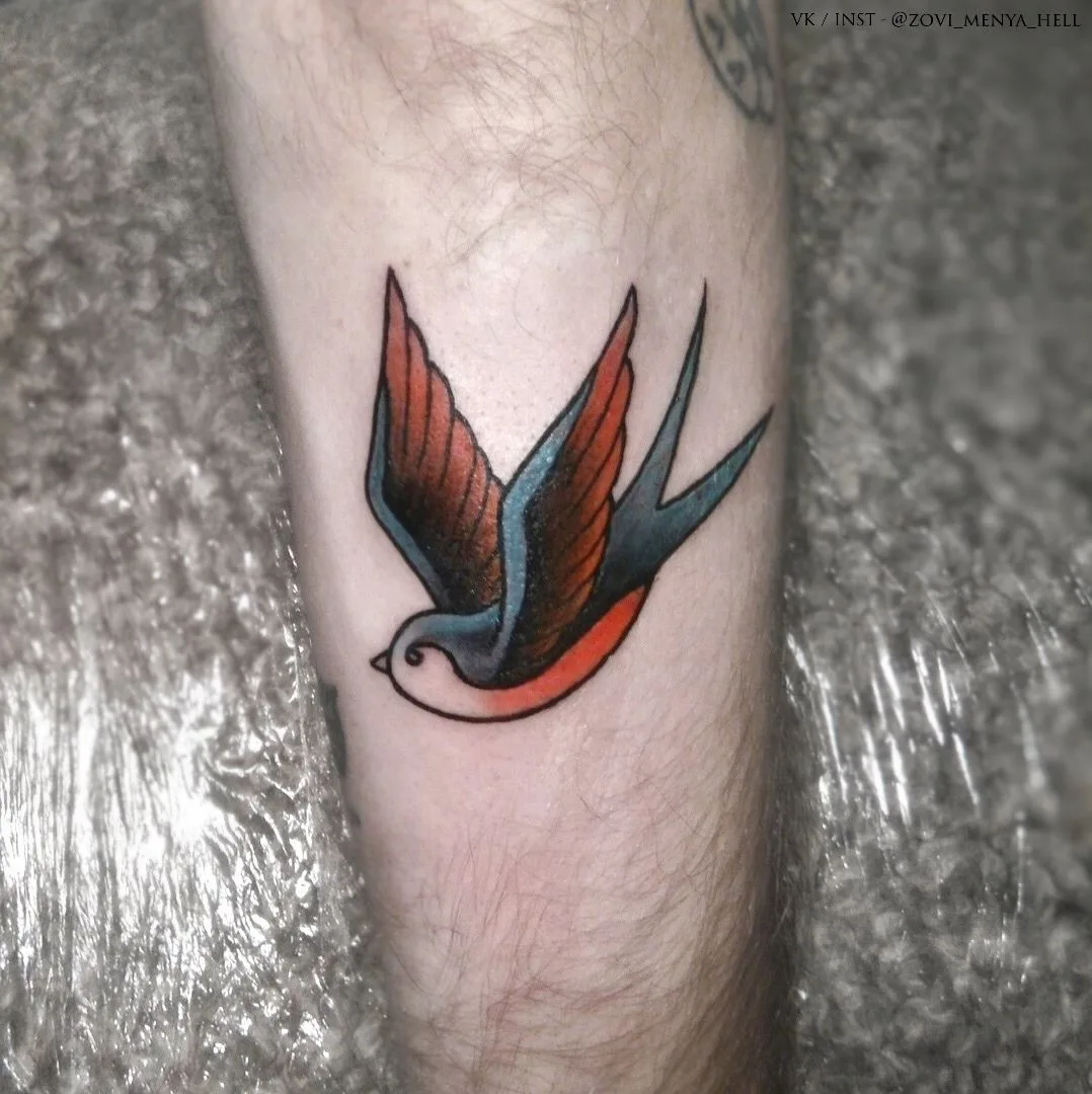 Ein klassisches Traditional-Tattoo einer Schwalbe im Flug mit fetten schwarzen Konturen und leuchtenden Farben.
