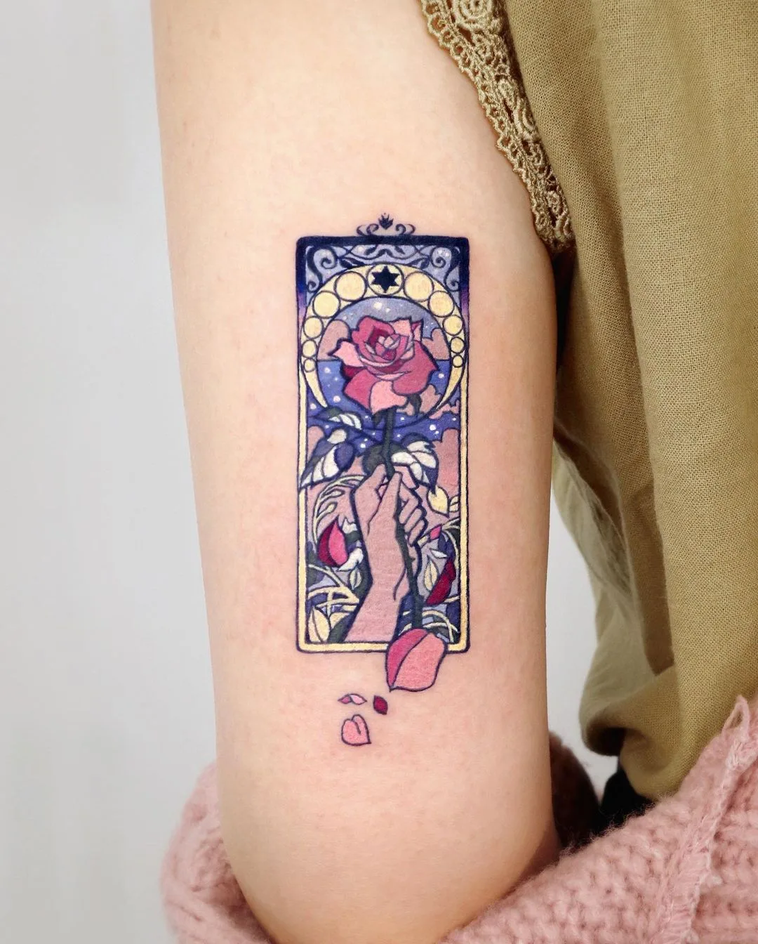 A vibrant tattoo depicting a rose held by hands with a stained glass aesthetic.