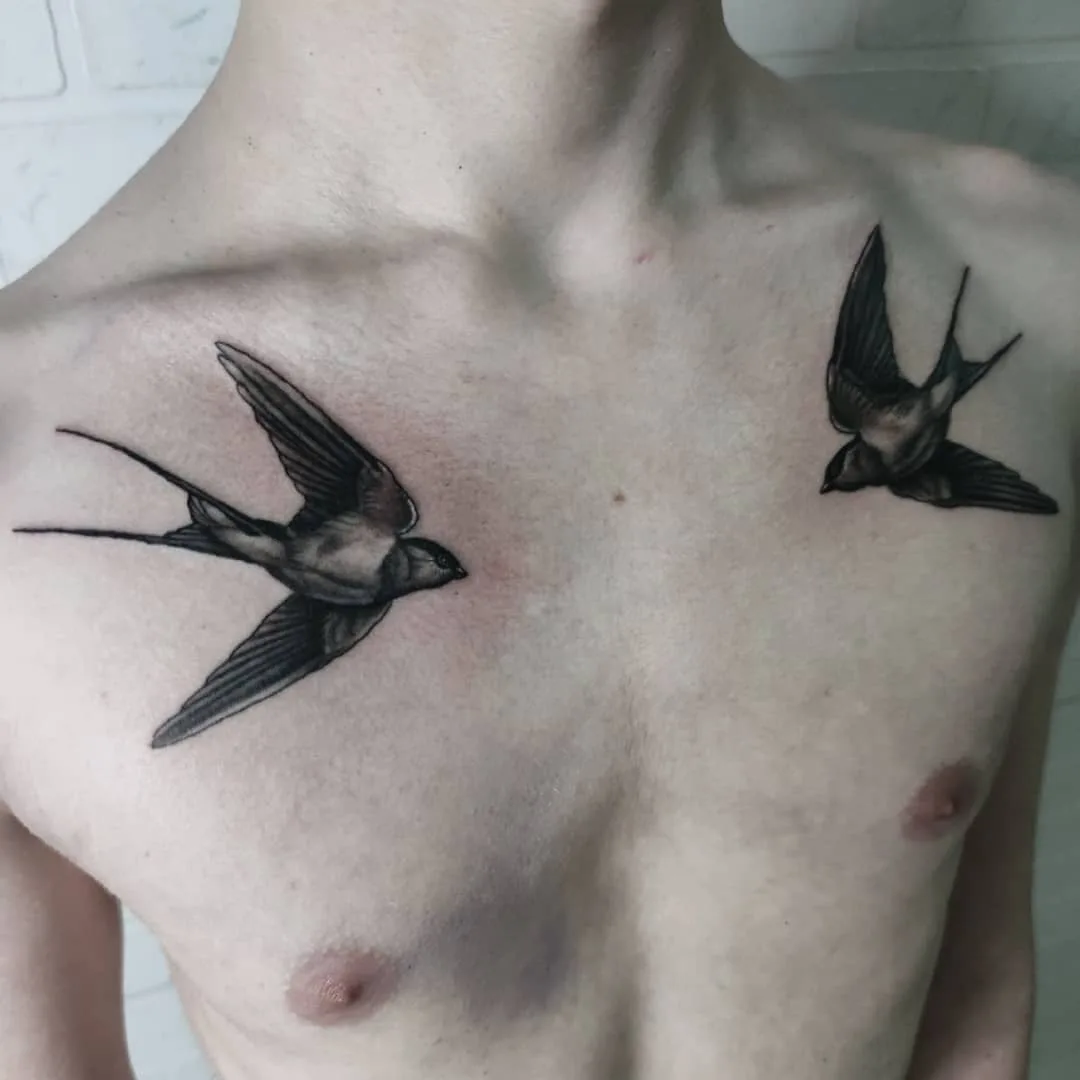 Due tatuaggi di rondini in volo posizionati simmetricamente sul petto, realizzati in bianco e nero con stile realistico.