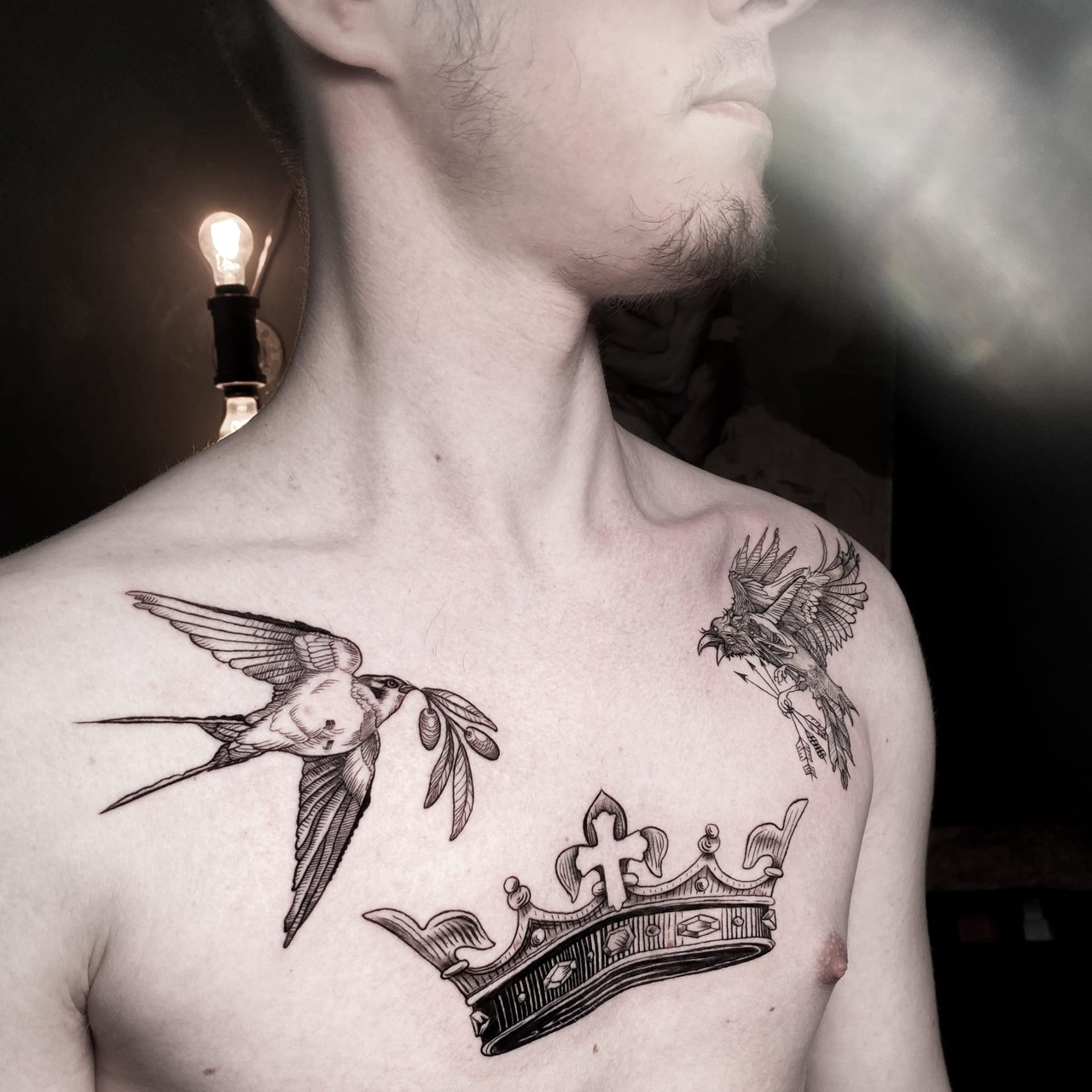 Ein Schwarz-Grau-Tattoo mit einer Schwalbe, die einen Olivenzweig trägt, einem Vogel mit Pfeilen und einer Krone.