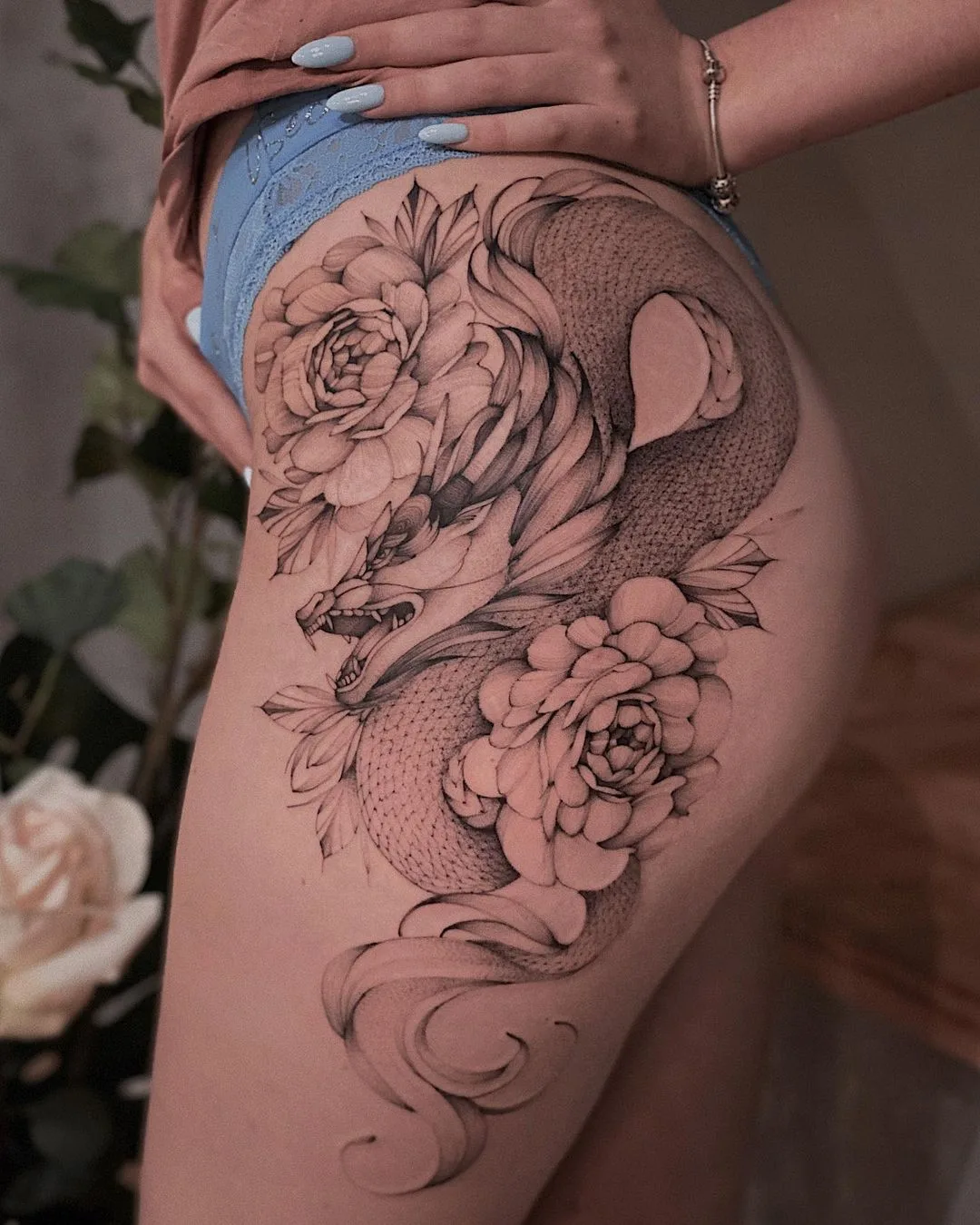 Tatuagem na coxa com dragão e flores