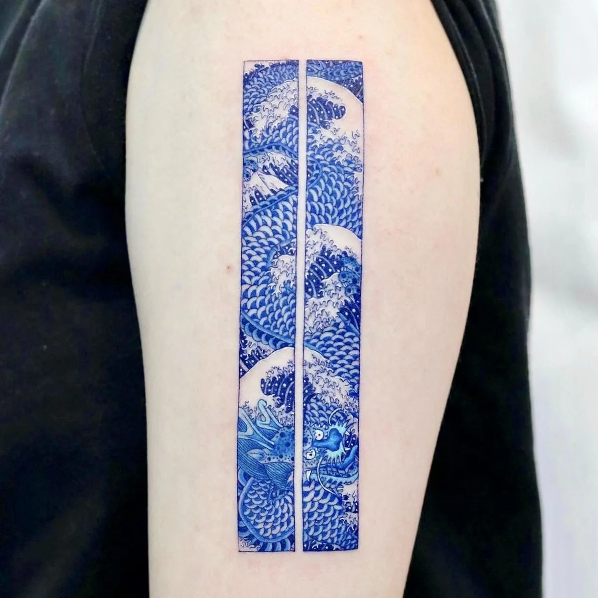 A blue and white tattoo featuring a dragon and waves in a Japanese-inspired style.