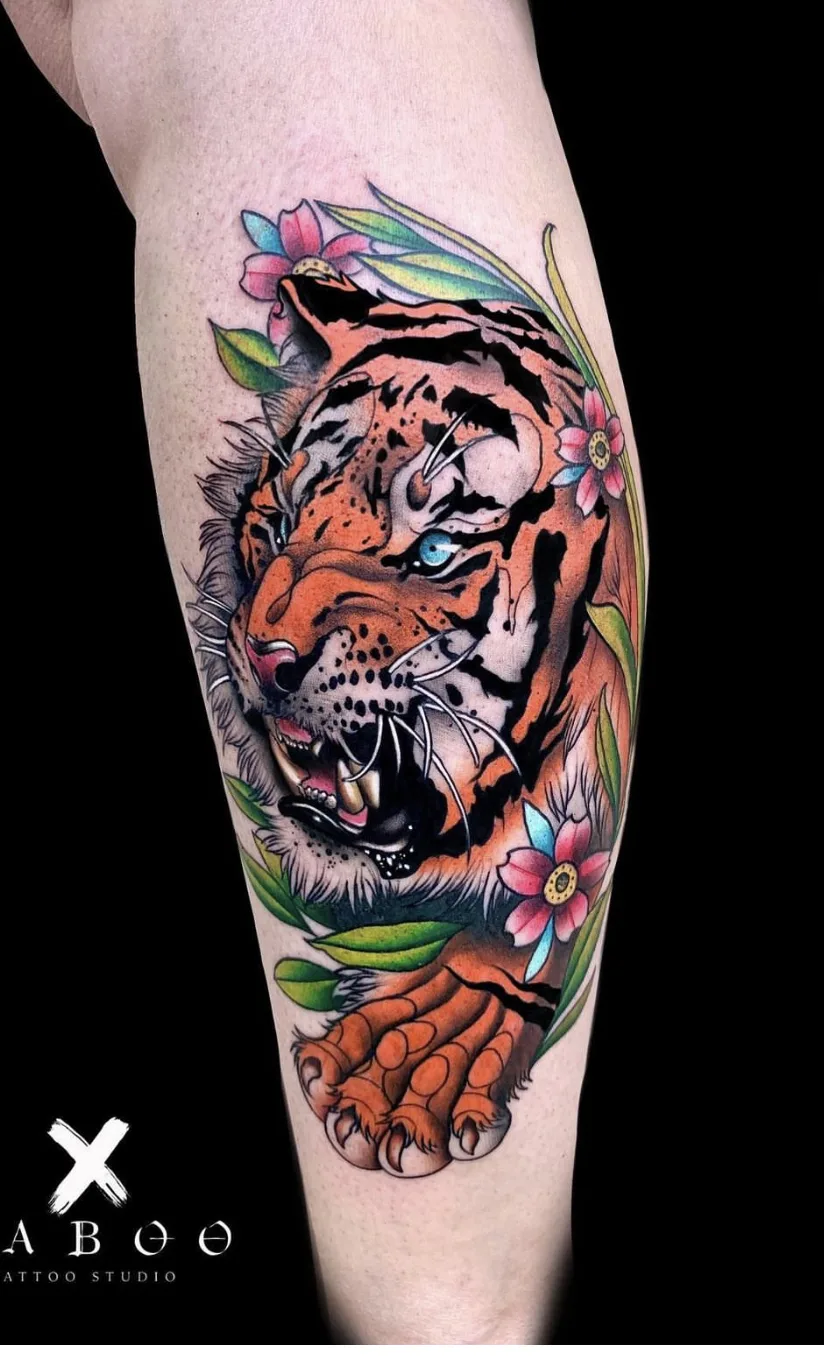 A vibrant neo-traditional tattoo of a snarling tiger surrounded by flowers and foliage in rich, saturated colours.