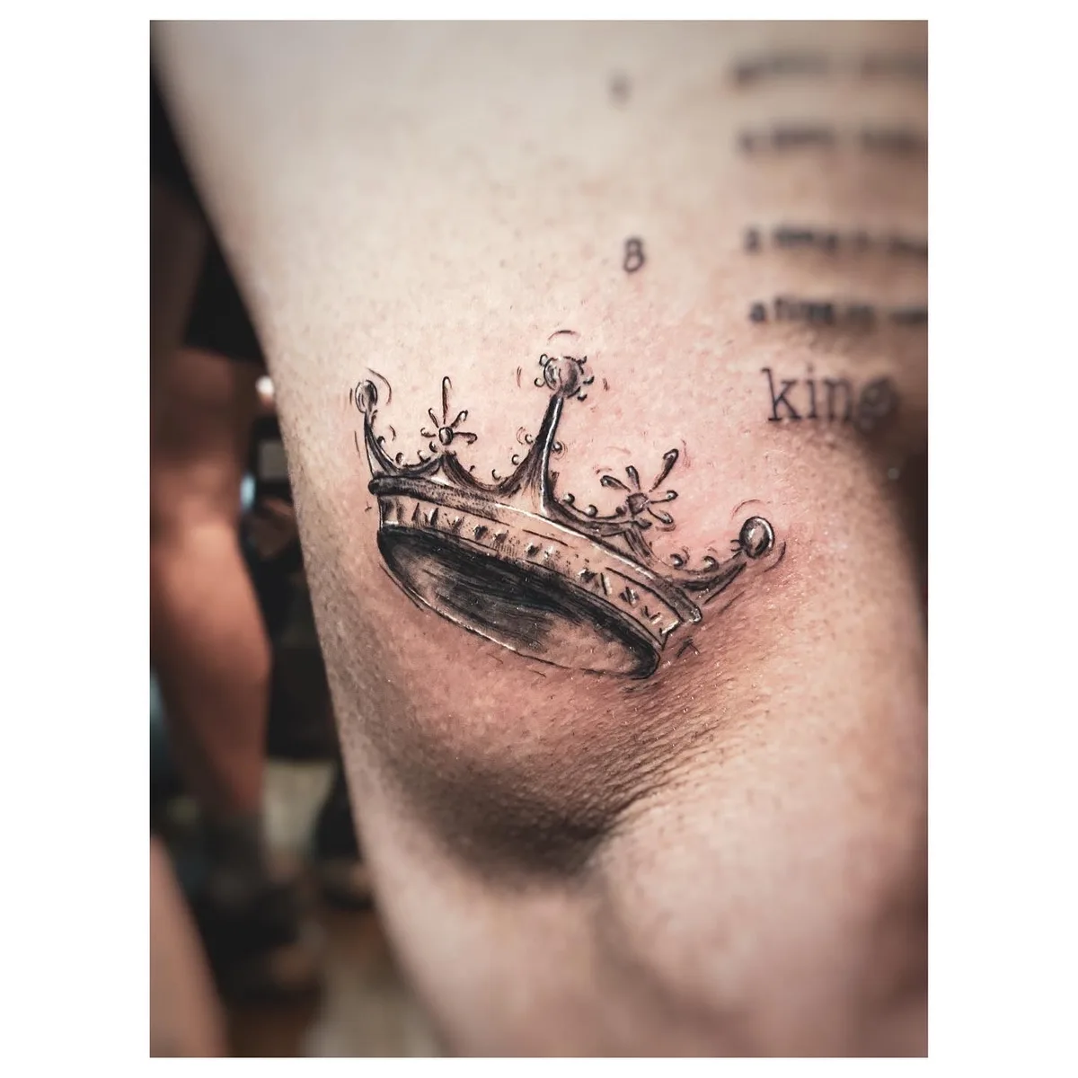 Tatuaggio di una corona in stile sketch in bianco e nero, posizionato sul braccio superiore con tratti a mano libera.