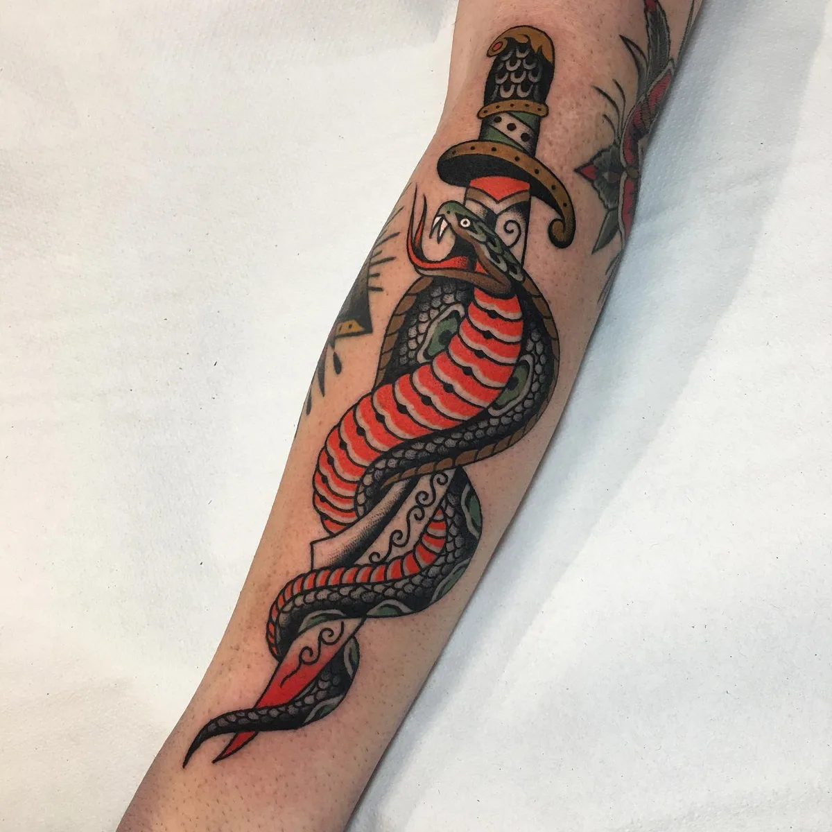 Tatouage de style traditionnel représentant un serpent enroulé autour d'un poignard.