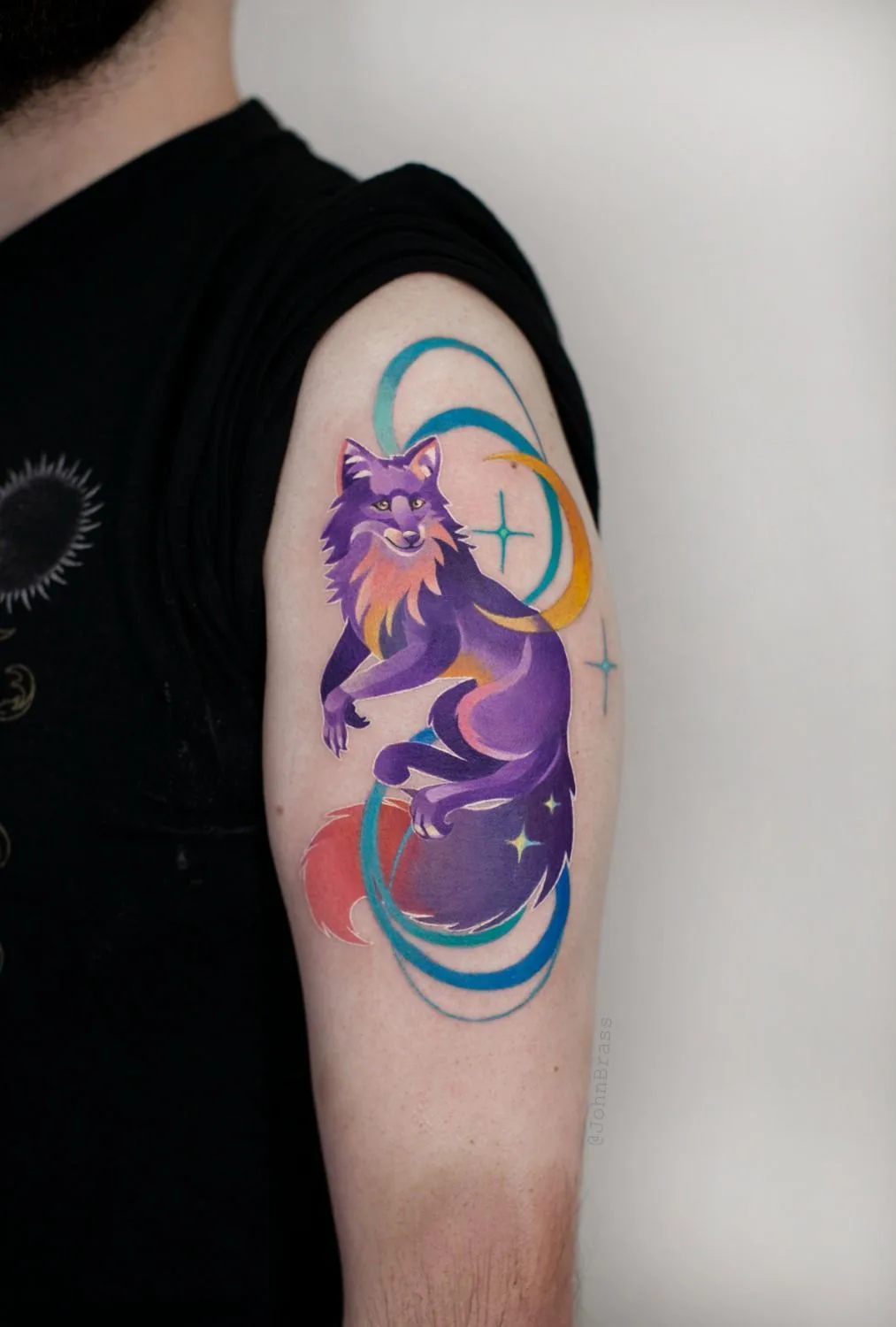 A colourful tattoo of a stylised fox with celestial and geometric elements, rendered in watercolor-like shading.