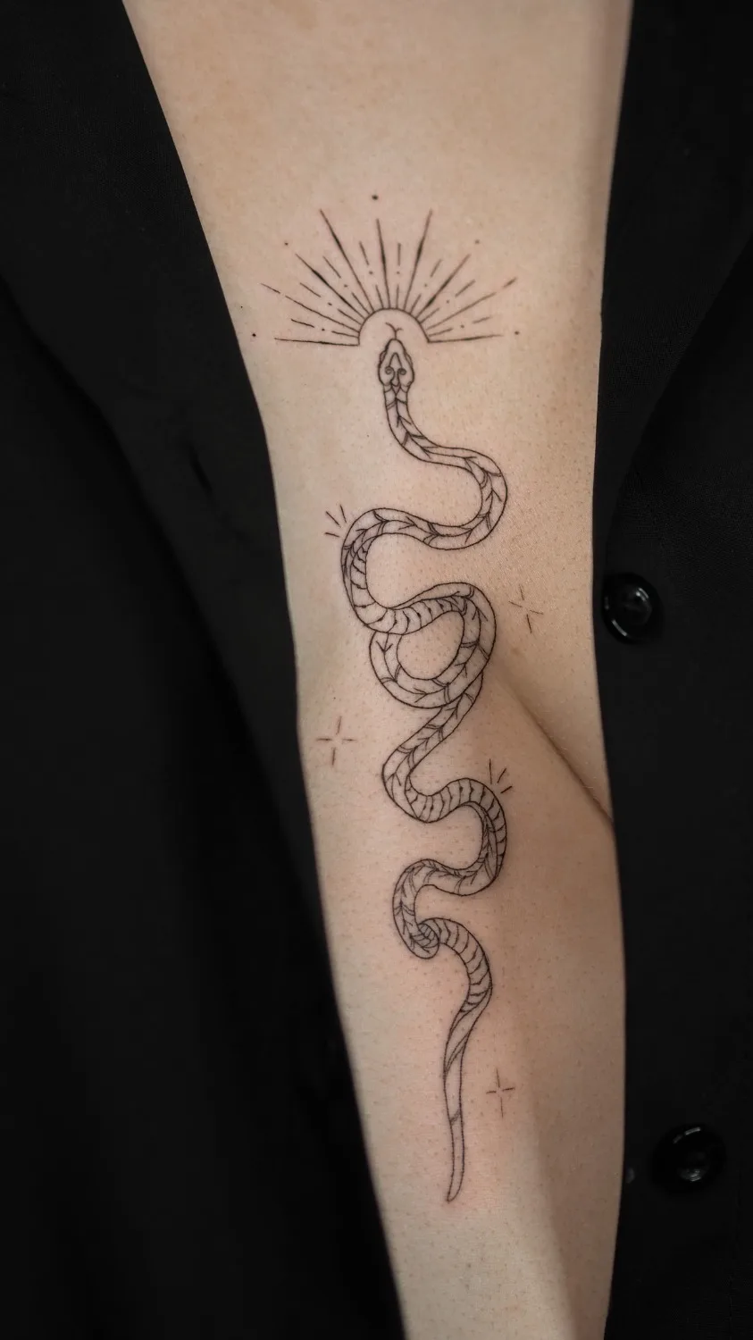 A delicate minimalist linework tattoo featuring a snake and a sunburst design, executed in a single fine line with a clean, understated aesthetic.