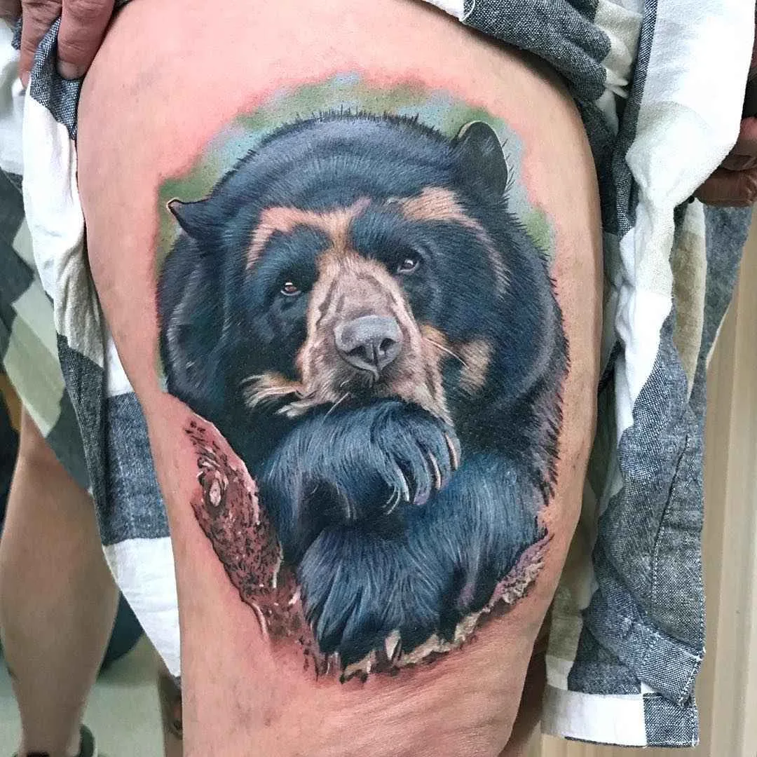 A realistic portrait of a bear tattooed on the thigh with highly detailed fur texture and facial features.