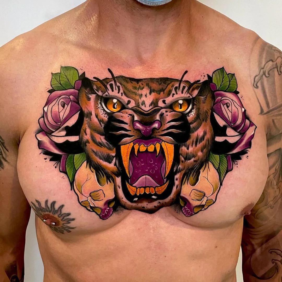 A vibrant neo-traditional chest tattoo featuring a snarling tiger head flanked by roses and skulls in bold colour.