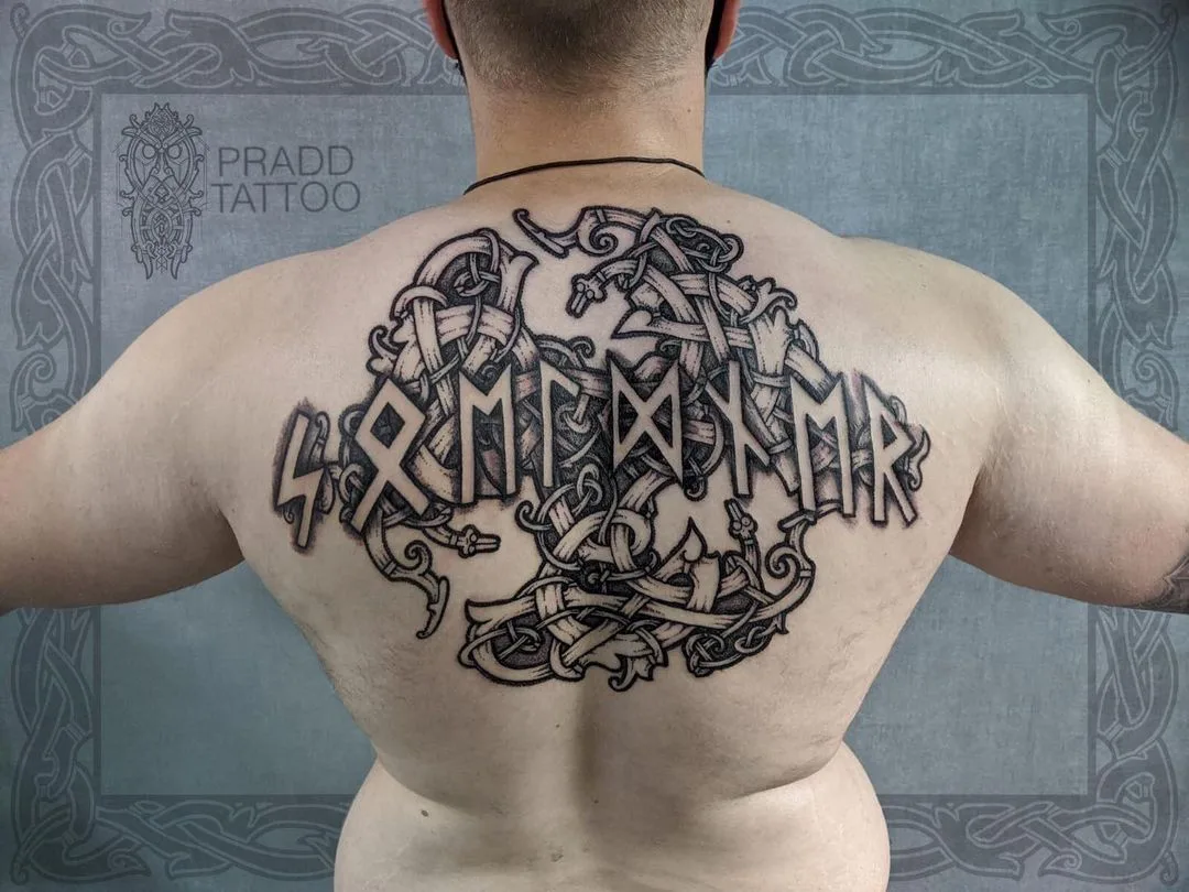 Tatouage en noir et gris avec lettres runiques et entrelacs celtiques, centré sur le haut du dos.