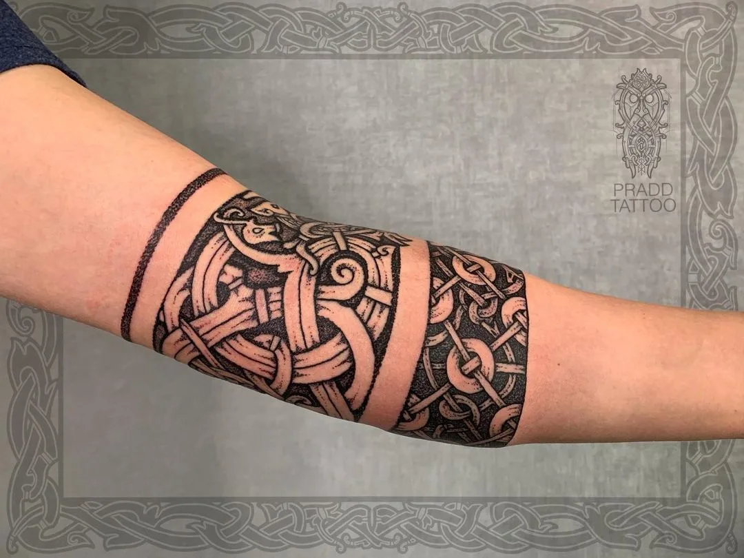 Ein Blackwork-Tattoo mit keltischem Flechtband und Tiermotiv, das den Unterarm umschließt.