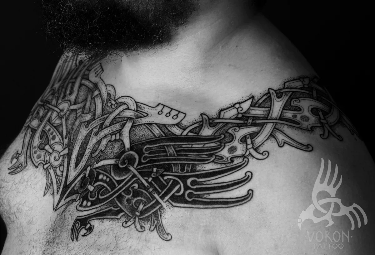 Tatouage en noir et gris avec entrelacs celtiques complexes et motif d'oiseau, couvrant une grande partie de la poitrine et de l'épaule.