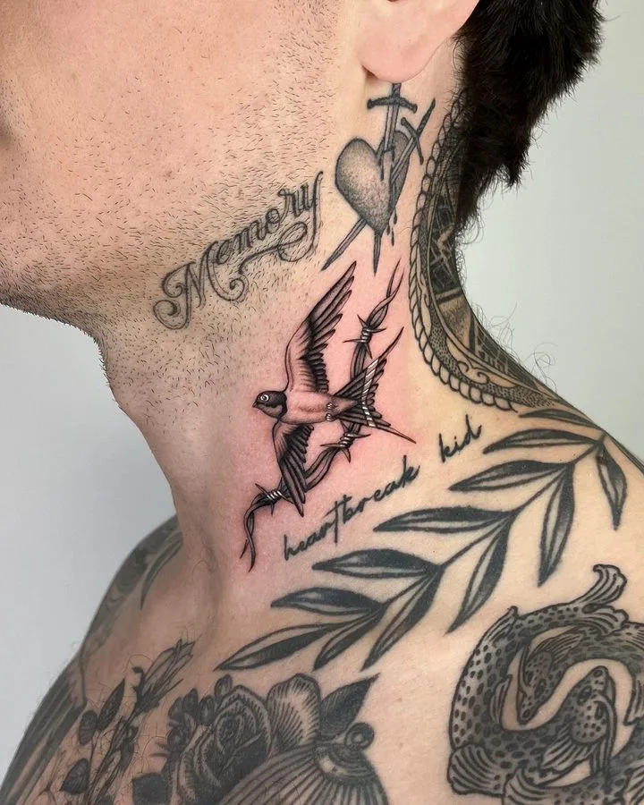 Ein Schwarz-Grau-Tattoo einer Schwalbe, die in Stacheldraht verwickelt ist, mit einem von Schwertern durchbohrten Herz und Schriftzug.