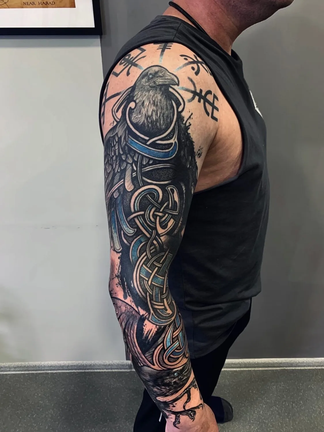 Tatouage blackwork détaillé représentant un corbeau avec entrelacs celtiques et runes, couvrant tout le bras.