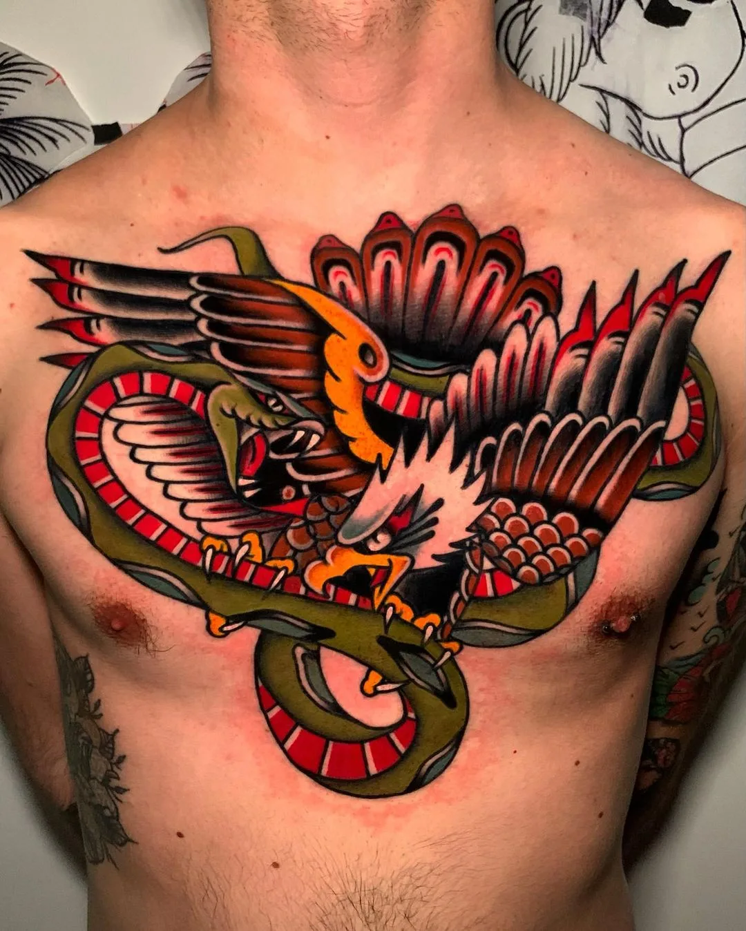 Traditional style chest tattoo of an eagle and snake intertwined, with bold outlines and a limited color palette.