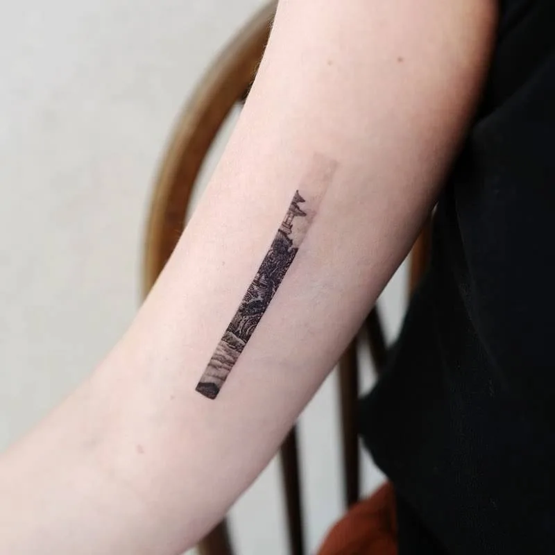 A detailed blackwork tattoo depicting a landscape scene inspired by engraving techniques.