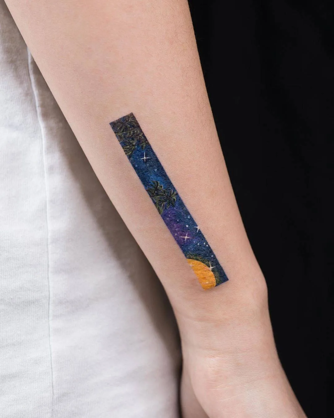 A colorful illustrative tattoo depicting a night sky scene with palm trees and a moon.