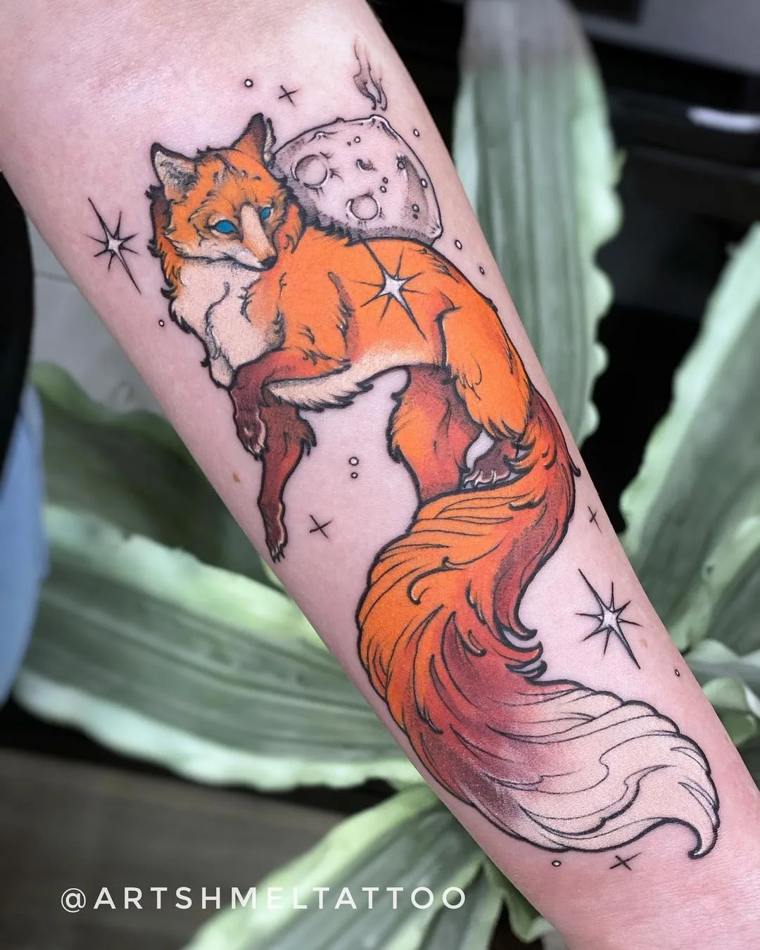 A watercolor-style tattoo of a stylised fox with a moon motif on its back, rendered in flowing washes of colour.