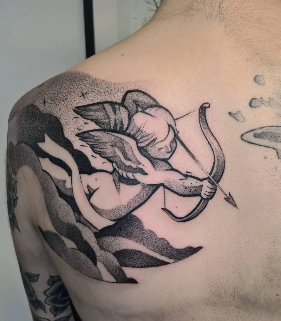 Чёрно-серая татуировка ангела с луком и стрелой, выполненная в технике дотворк.