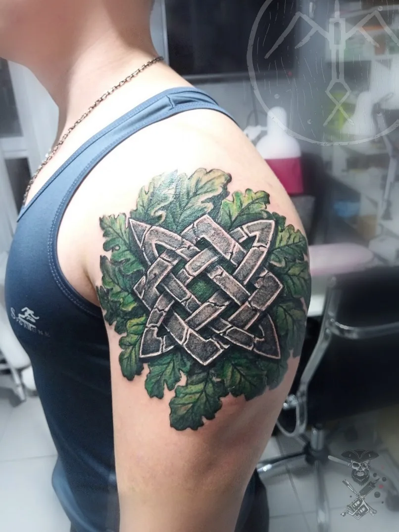 Ein keltisches Knotenmuster-Tattoo, umgeben von grünen Blättern, detailliert und ornamental ausgeführt.