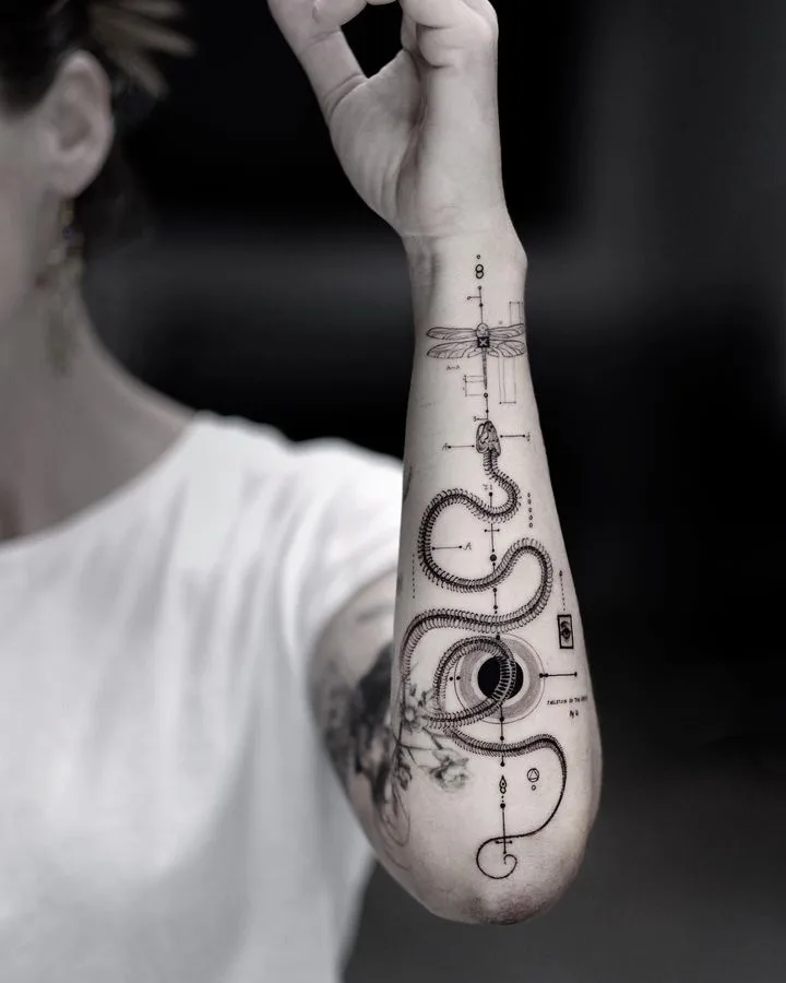 Tatouage noir et gris détaillé représentant un serpent, un œil et une libellule avec des éléments géométriques.
