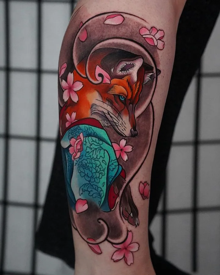 A colourful tattoo of a fox wearing a kimono surrounded by cherry blossoms, rendered in a Japanese-inspired illustrative style.