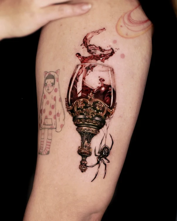 Illustrative Wine glass, Spider tattoo on Upper Arm