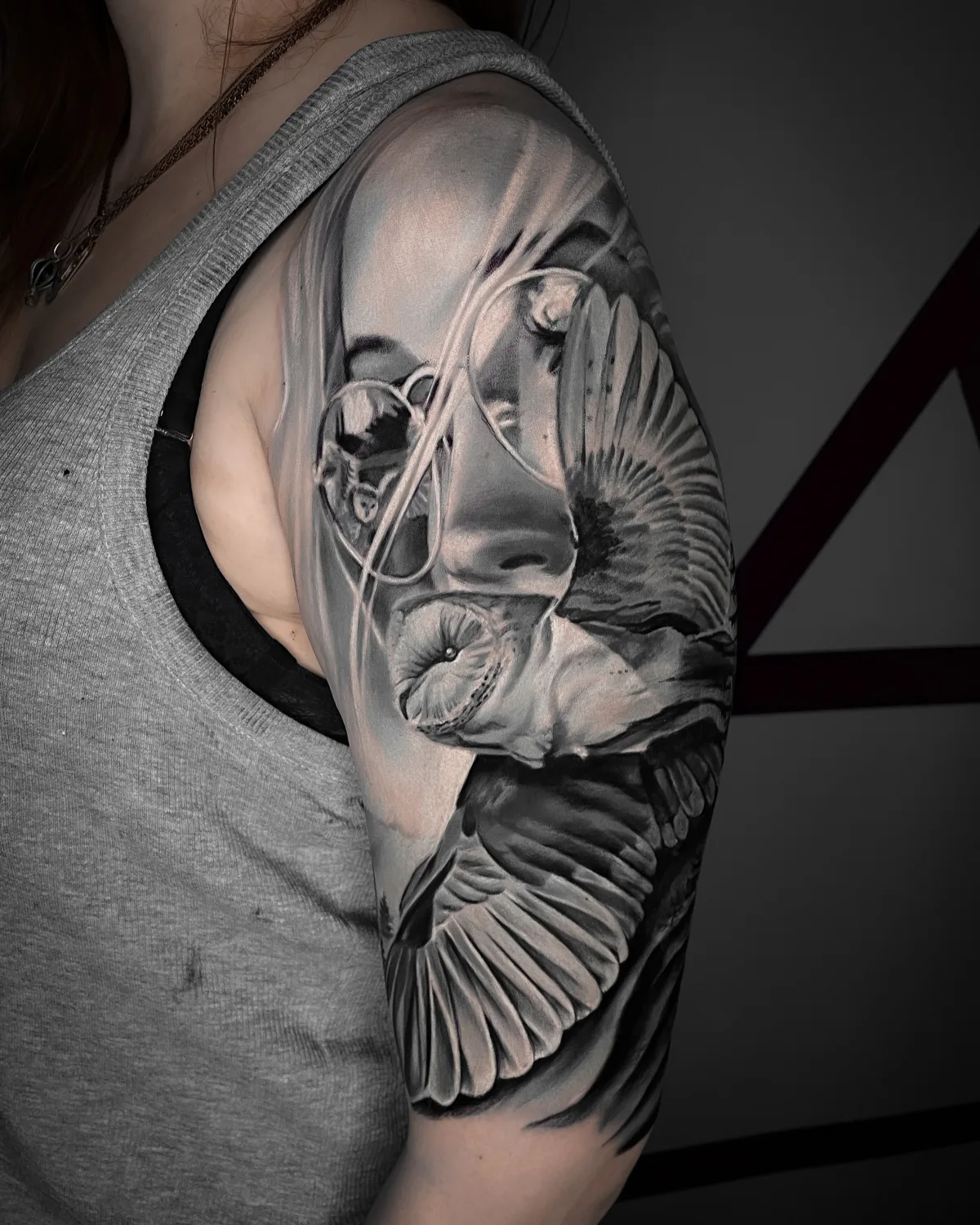 A realistic black and grey tattoo combining a woman's portrait with an owl integrated into the composition, covering a large area of skin.