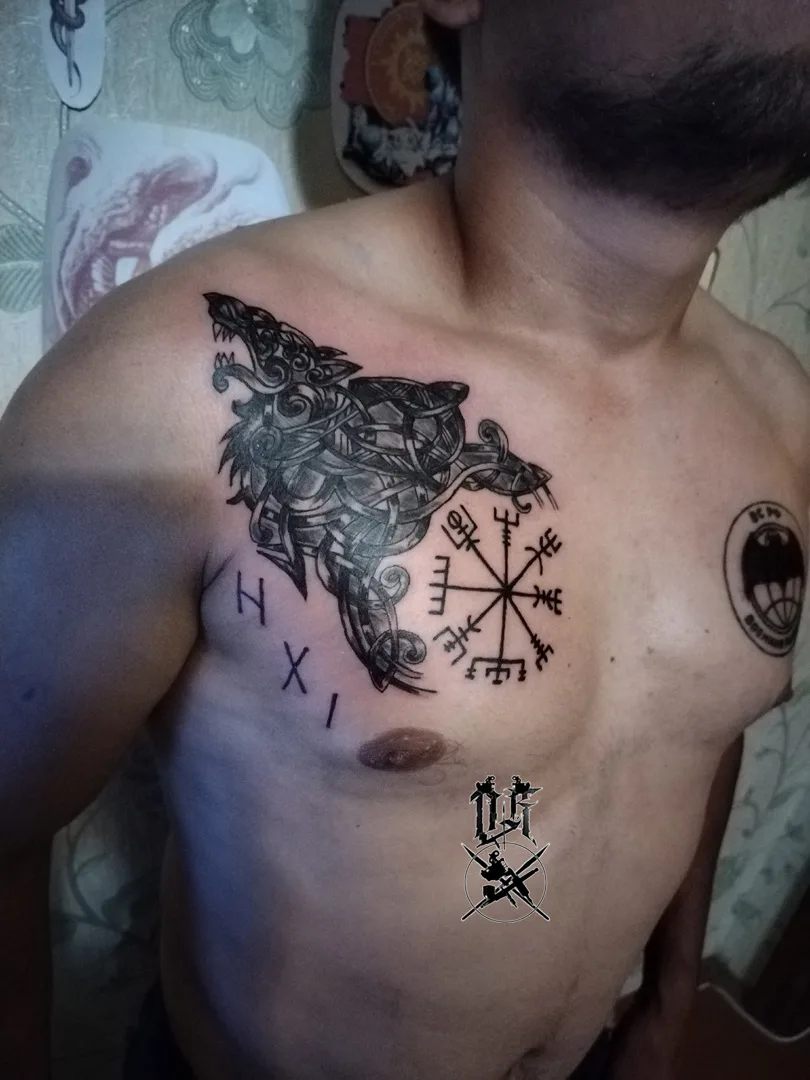 Ein Blackwork-Tattoo auf der Brust mit einem Wolf, keltischem Knotenmuster und einem Kompasssymbol.