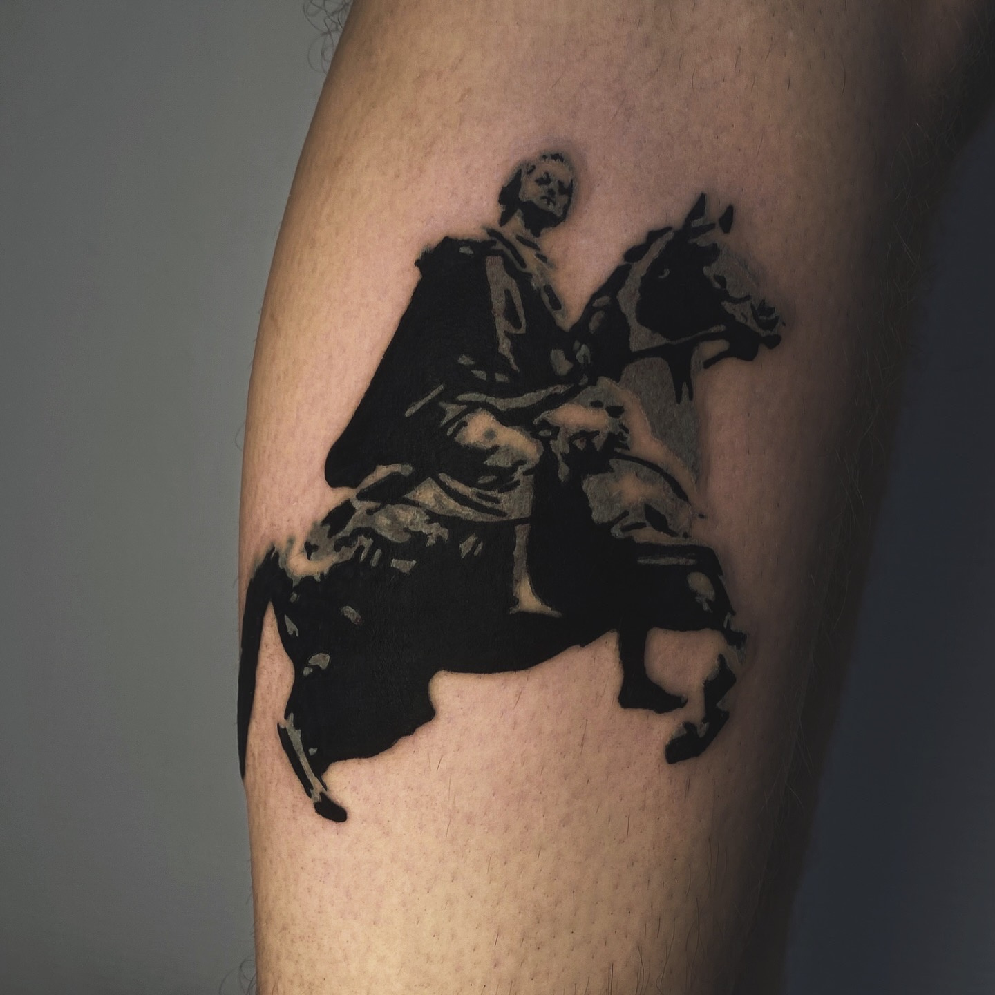 A blackwork tattoo depicting a figure on horseback rendered in a style reminiscent of a historical engraving.