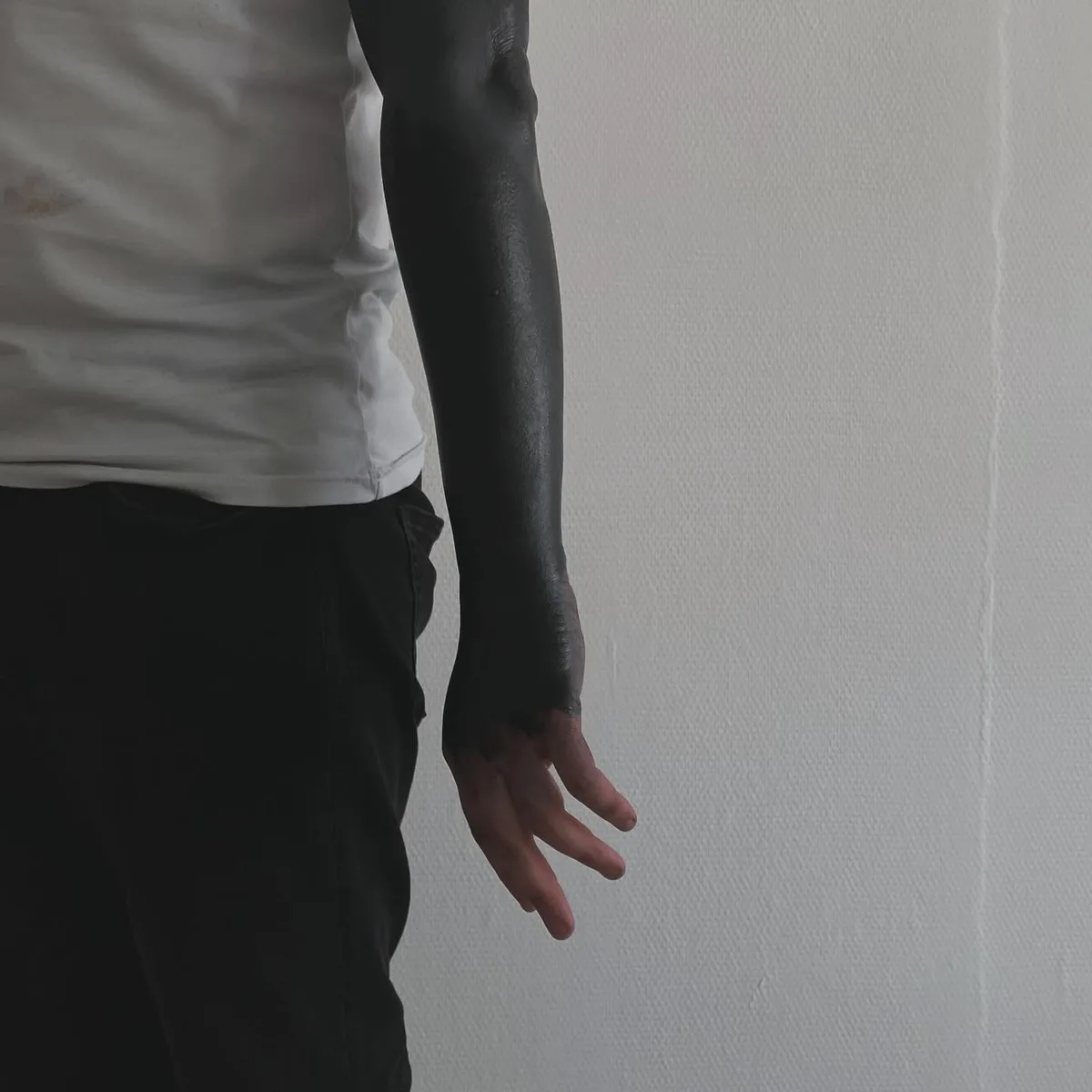 This tattoo is a full blackout sleeve, covering the entire arm in solid black ink.