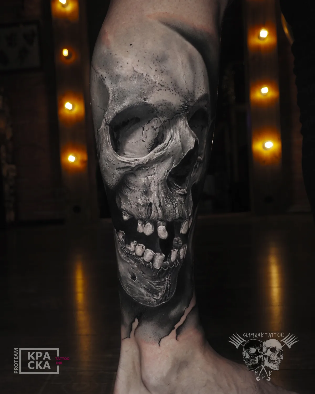 A highly detailed black and grey realistic skull tattoo placed on the calf, with expert shading and depth.