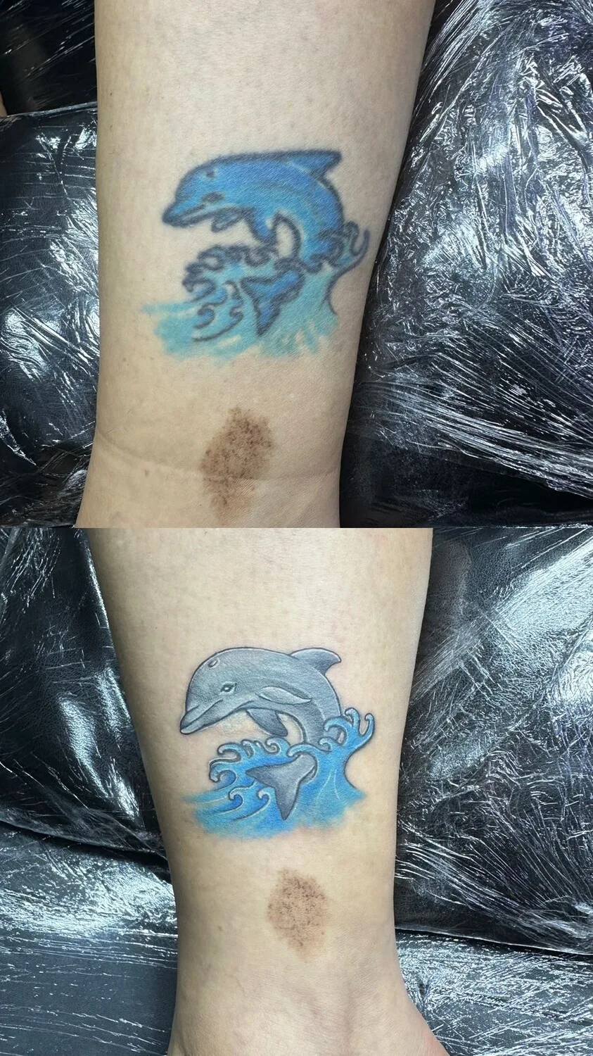 A watercolour-style tattoo of a dolphin leaping out of the water, used as a cover-up piece with vivid blue and teal tones.
