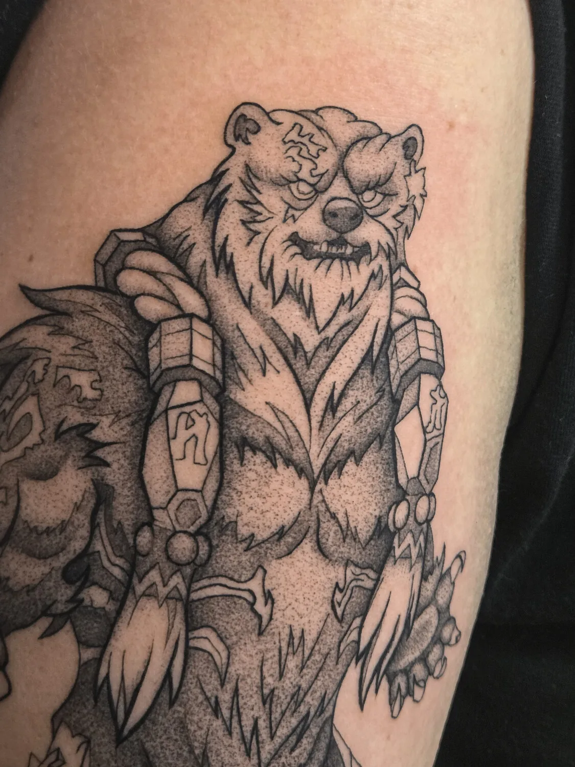 A detailed black and grey dotwork tattoo of a bear with armour and a fierce expression.
