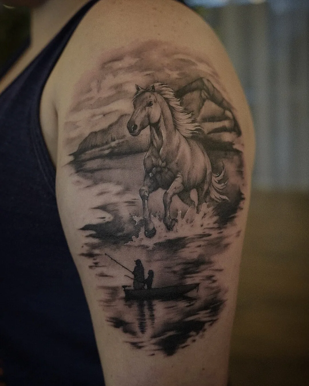 A detailed black and grey tattoo depicting a horse running through water above a scene of a boat with two figures fishing, rendered in a blackwork style.