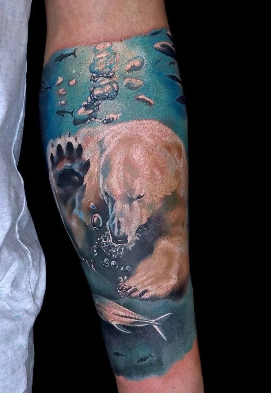 A realistic tattoo depicting a polar bear swimming underwater with fish and bubbles.