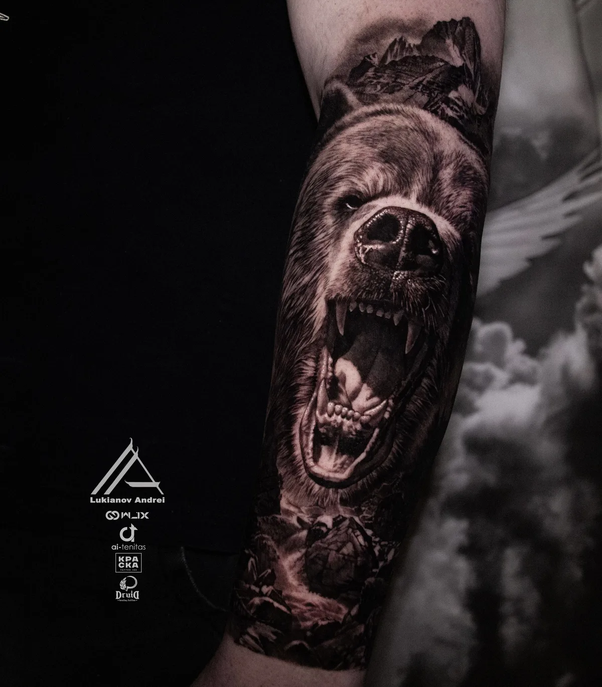A detailed black and grey tattoo of a roaring bear with mountains in the background.
