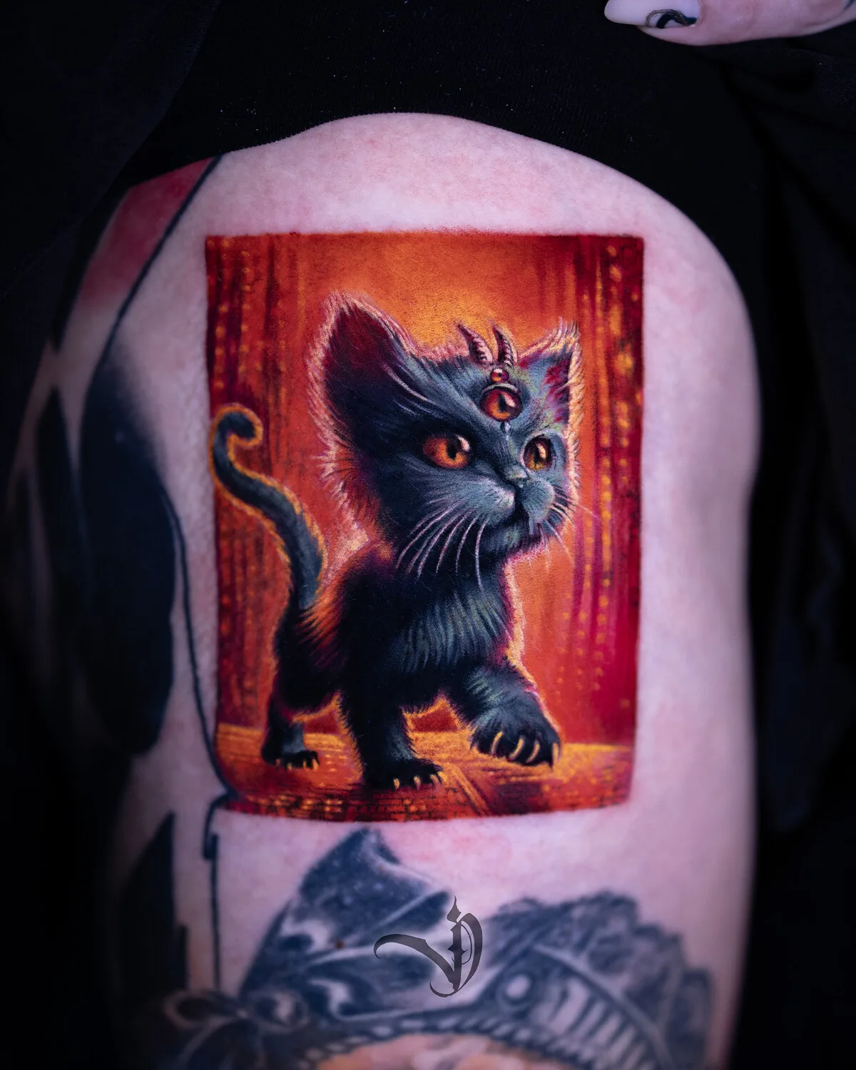 A detailed colorful tattoo of a black cat with three eyes and small horns set against a warm orange background, combining occult and illustrative elements.