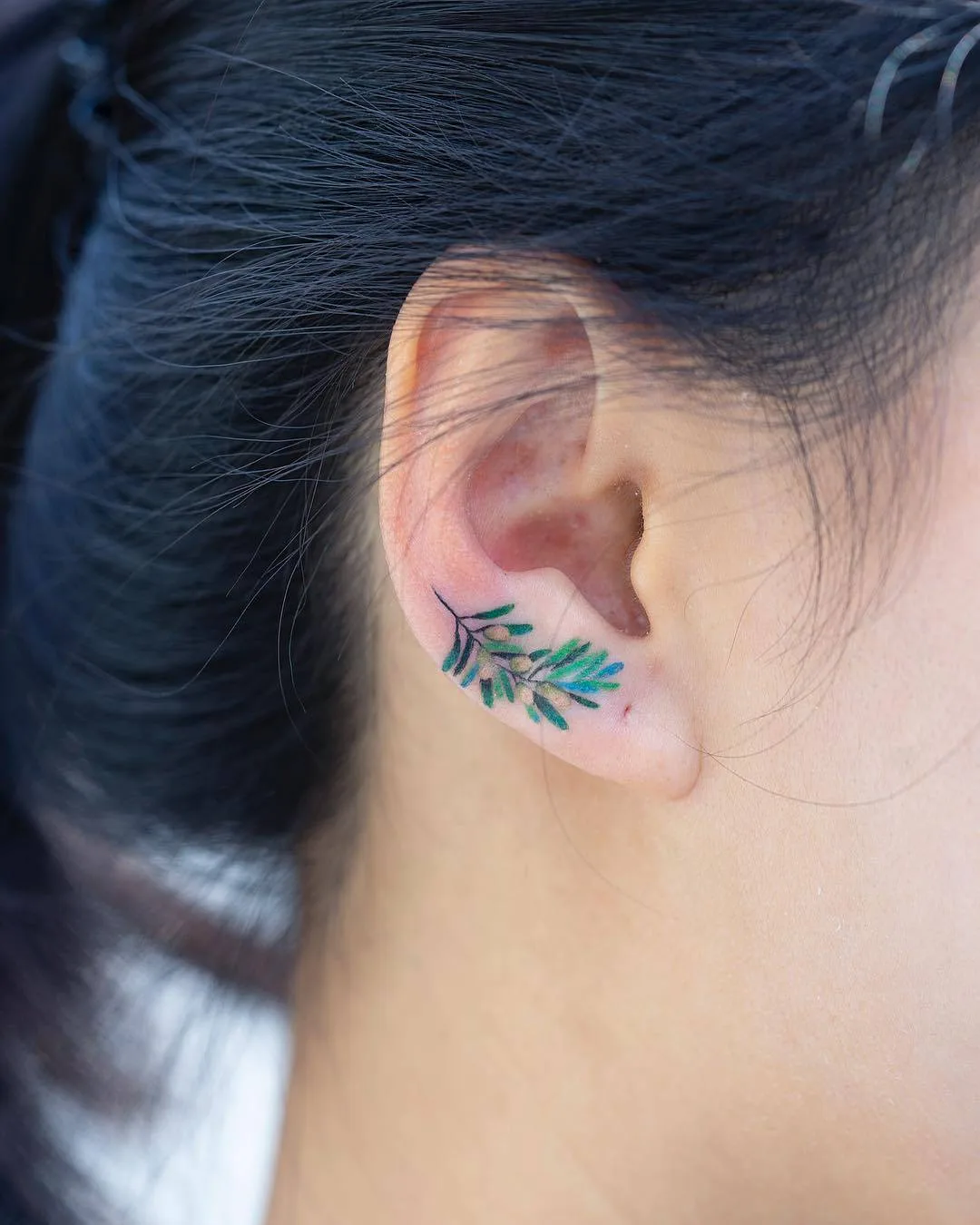 Artista del tatuaggio Zihee, tatuaggio colorato piccolo e minimalista sull'orecchio