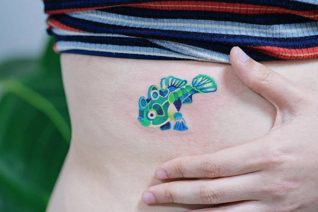 Artista del tatuaggio Zihee, tatuaggio colorato piccolo e minimalista di pesce
