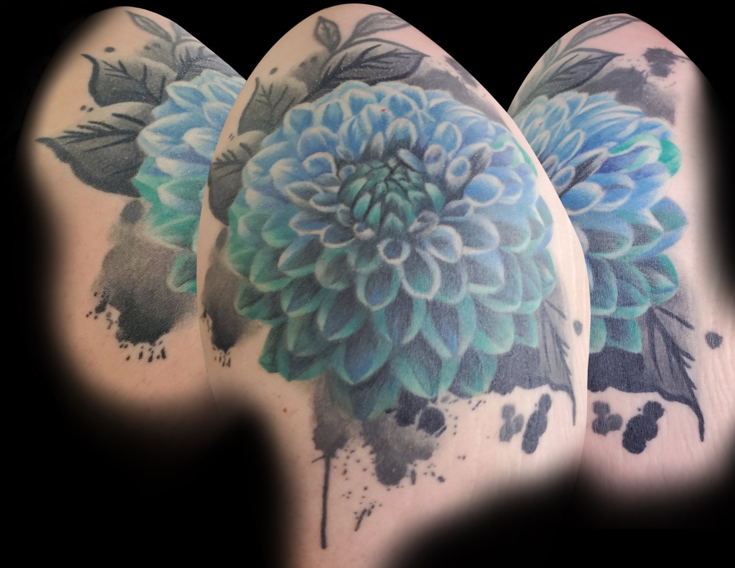 A large dahlia tattoo dominated by vivid blue and teal petals rendered in a watercolour style, with softer echoed versions of the flower in the background and dramatic black ink splatters surrounding the composition.