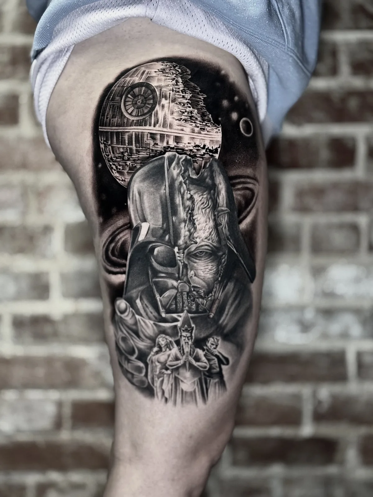 Black and grey realism thigh tattoo of Darth Vader with the Death Star